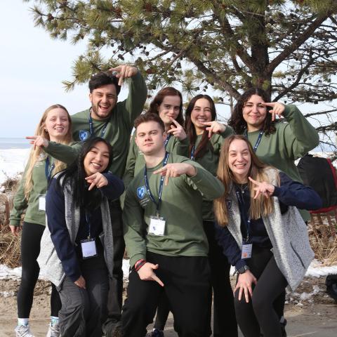 Group of students posing with their hands up.